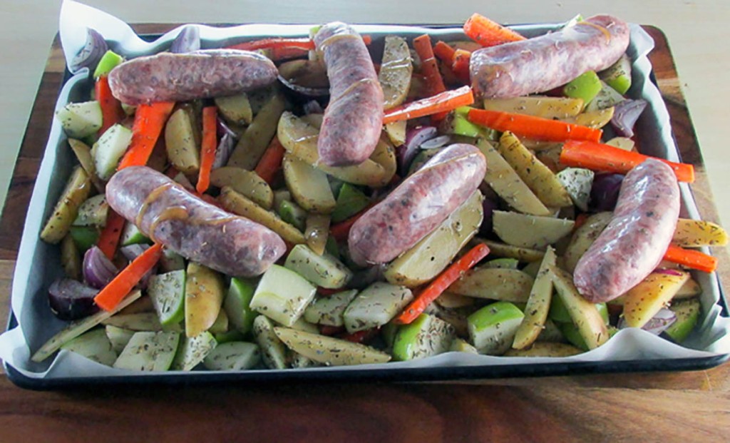 Place the vegetables on the baking tray and put the sausages on top of the vegetables. 